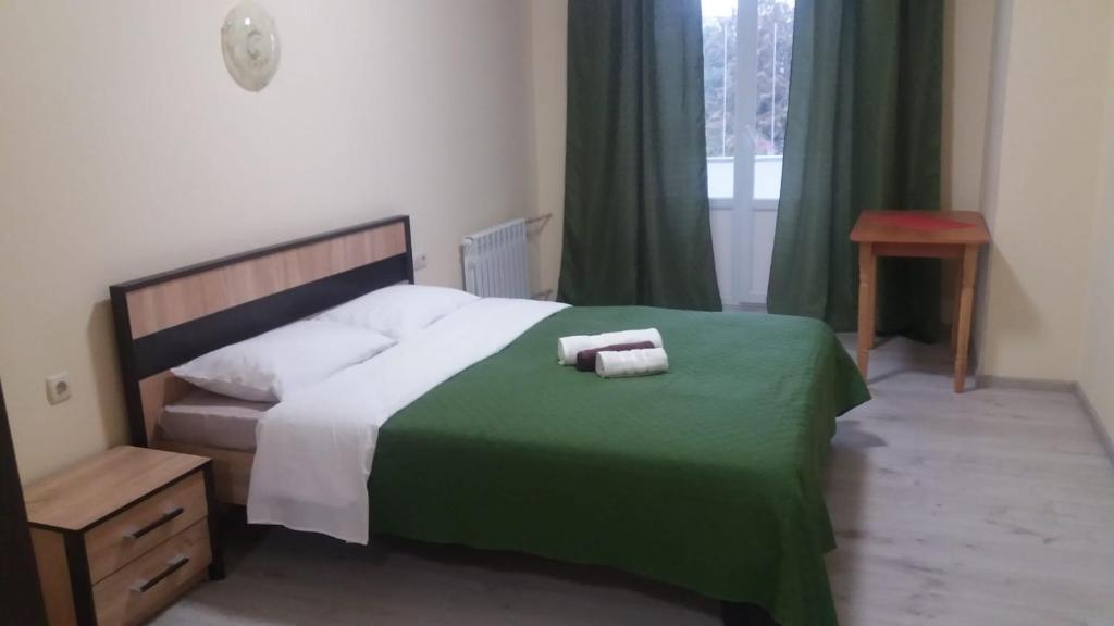 a bedroom with a large bed with a green blanket at Central Studio in Ternopil