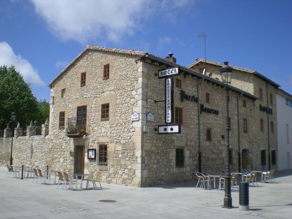 a stone building with tables and chairs in front of it at Hotel Puerta Romeros in Burgos