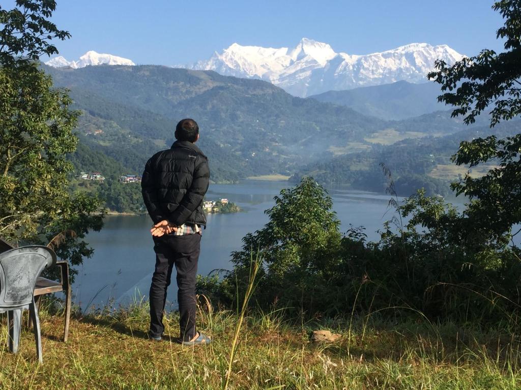 um homem parado no topo de uma colina com vista para um lago em Mount Fuji em Deorāli