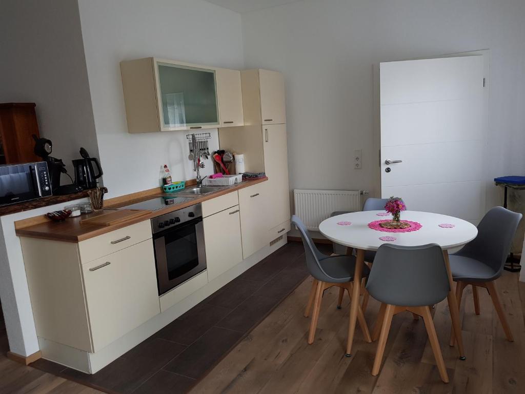 a kitchen with a table and chairs and a kitchen with white cabinets at Ferienwohnung an der Unditz 2 in Neuried