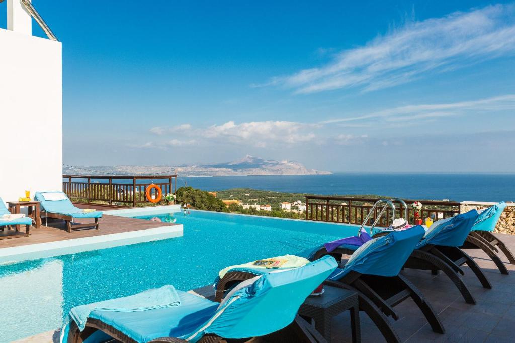 a pool with chairs and a view of the ocean at Ekaterini Vip Villa in Plaka