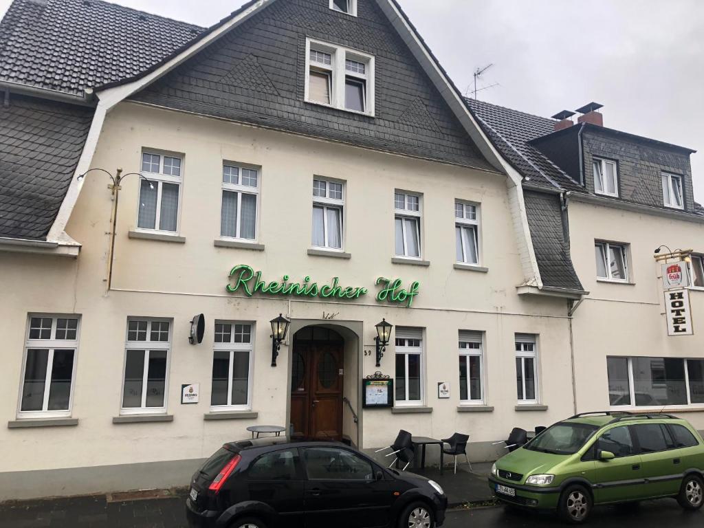 レバークーゼンにあるRheinischer Hofの建物の前に2台の車が駐車している