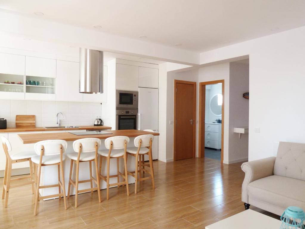 kuchnia i salon ze stołem i krzesłami w obiekcie Ocean Breeze Apartment w mieście Estoril
