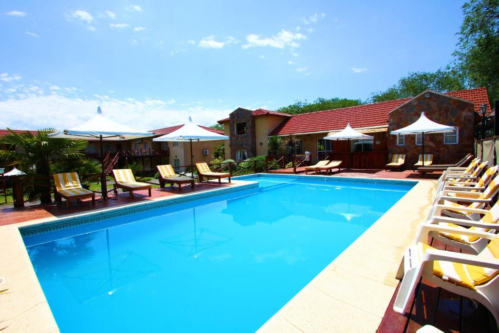 una piscina con tumbonas y sombrillas en Apart Hotel Las Palmeras en Villa General Belgrano