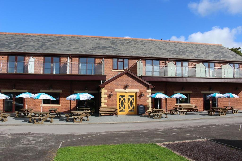 a building with tables and umbrellas in front of it at Riverside Park & Country Club in South Molton