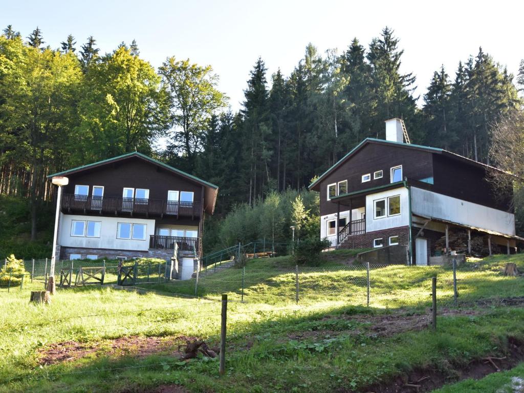 two houses in a field with trees in the background at Chalet in Dolní Brusnice near Ski Lift in Bílá Třemešná