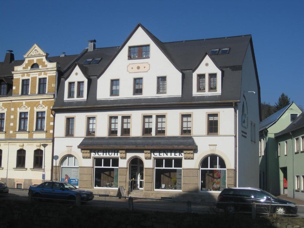 un grande edificio bianco con macchine parcheggiate di fronte di Ferienwohnung am Schwarzwasser a Schwarzenberg