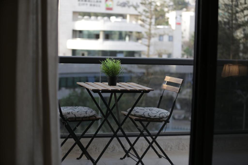 Ramallah Modern Apartment في رام الله: طاولة مع كرسيين ونصب الفخار على الشرفة