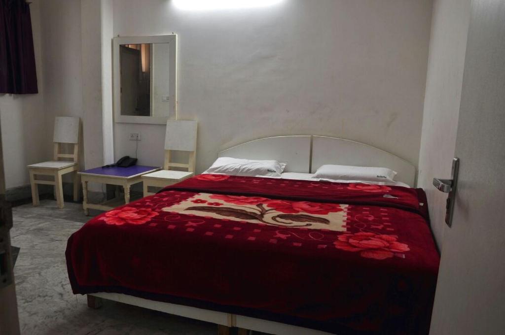 una camera da letto con un grande letto con una coperta rossa di Hotel Green Palace New a Nuova Delhi