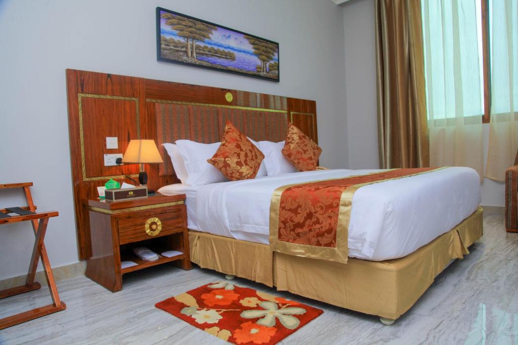 une chambre d'hôtel avec un grand lit et une table dans l'établissement Tiffany Diamond Hotels LTD - Makunganya, à Dar es Salaam