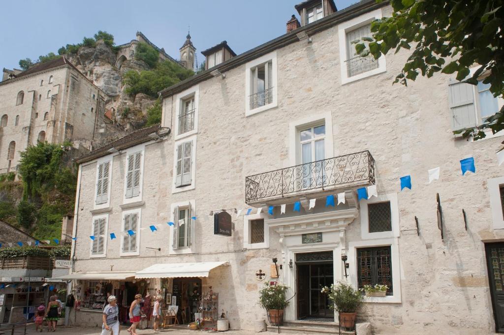 duży kamienny budynek z ludźmi idącymi przed nim w obiekcie Hotel Beau Site - Rocamadour w mieście Rocamadour