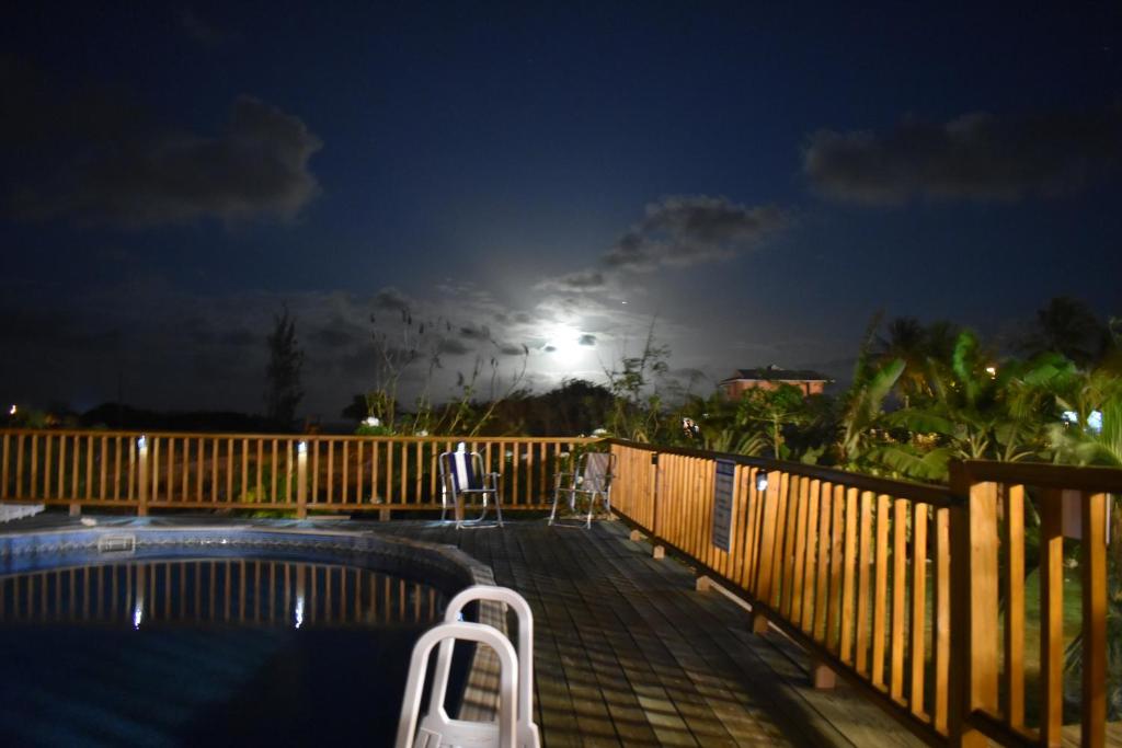 a deck with a pool and a fence at night at The Pool House in Saint Philip