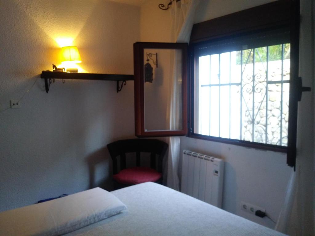 um quarto com uma cama, uma janela e uma cadeira em Ca Bernia em Bernia