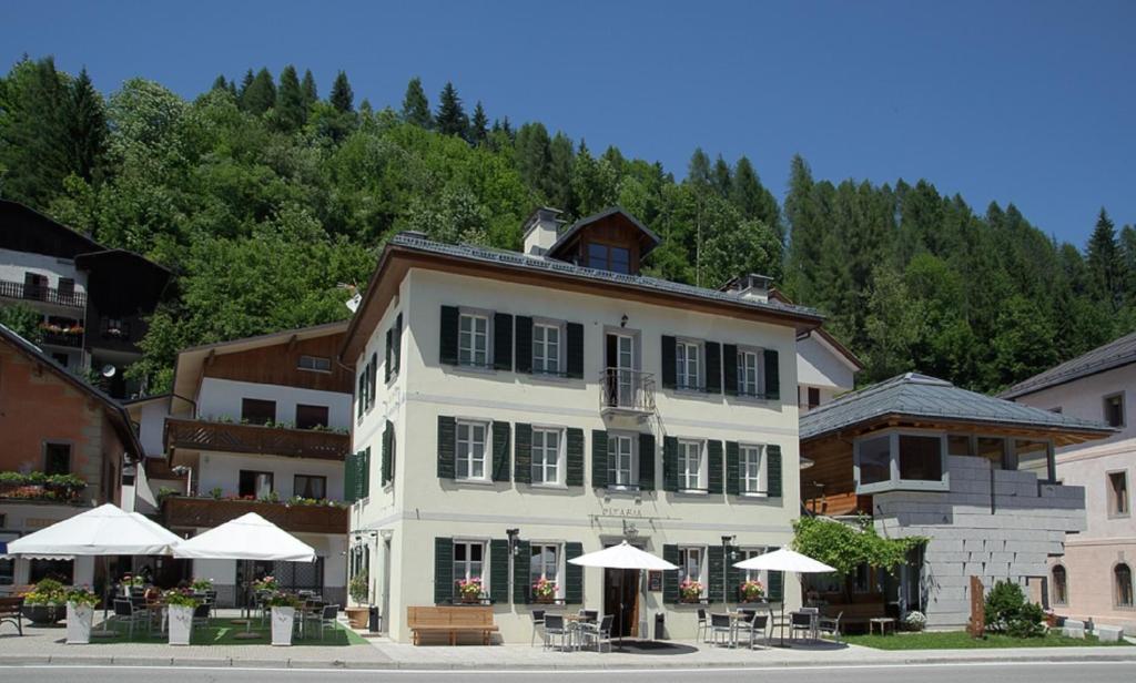 a white building with tables and umbrellas in front of it at Locanda Tana de 'l Ors in Val di Zoldo