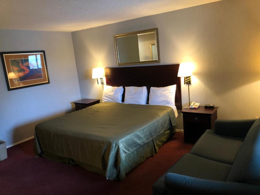 um quarto de hotel com uma cama e uma cadeira em Latham Inn em Latham