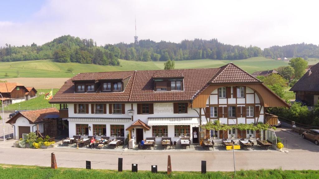 ein großes Gebäude mit Tischen und Stühlen davor in der Unterkunft Alpenblick Ferenberg Bern in Stettlen