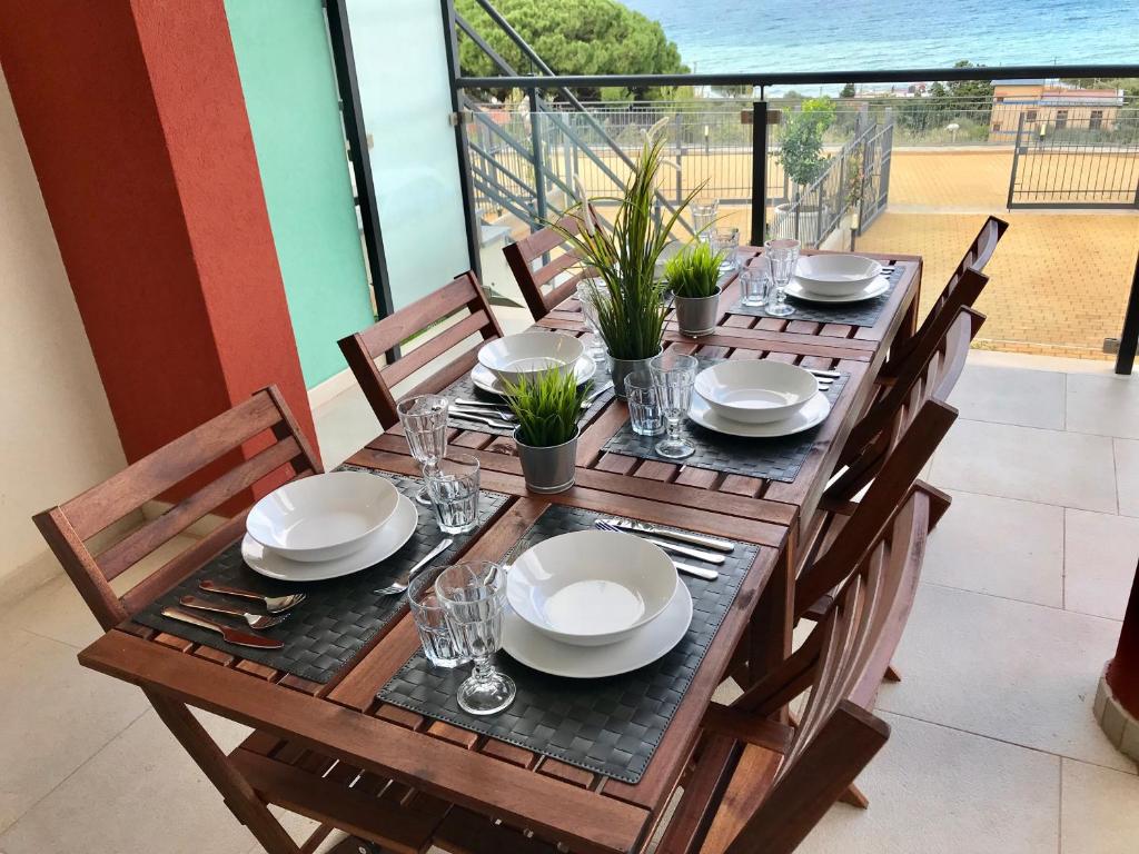 un tavolo in legno con piatti e bicchieri su un balcone di Red Luxury in Borgo Guardiola near Cefalù a Mandra Capreria