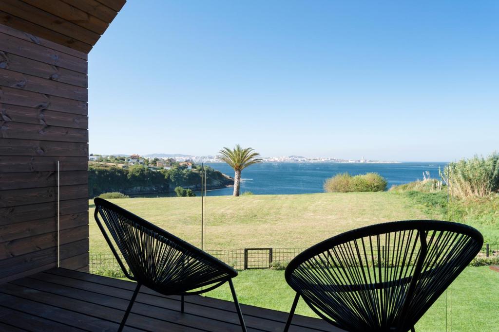 2 sillas en un porche con vistas al océano en Cabañas de Canide, en A Coruña