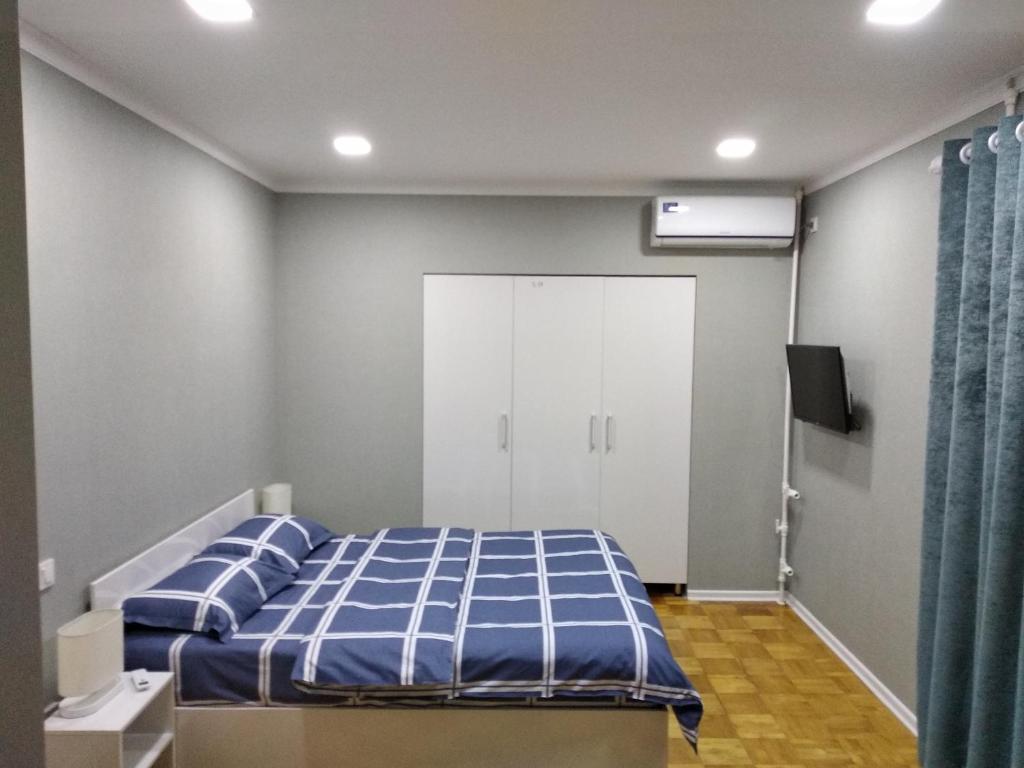 a bedroom with a bed with blue sheets and a door at Apartment on Oloy 11 in Tashkent