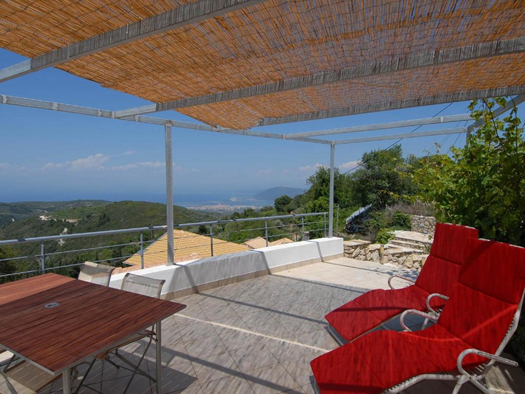 a patio with red chairs and a wooden table at Ferienhaus in Kavalos in Kávallos