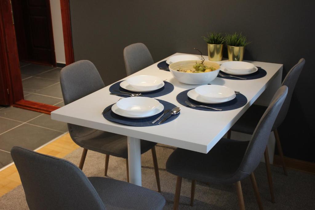 4 Seasons Vlašić Lux Apartments في فلاسيتش: طاولة بيضاء مع كراسي وصحن من الطعام عليها