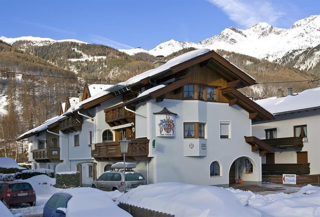 a large building with snow in front of a mountain at Appartement Cristallo in Sölden