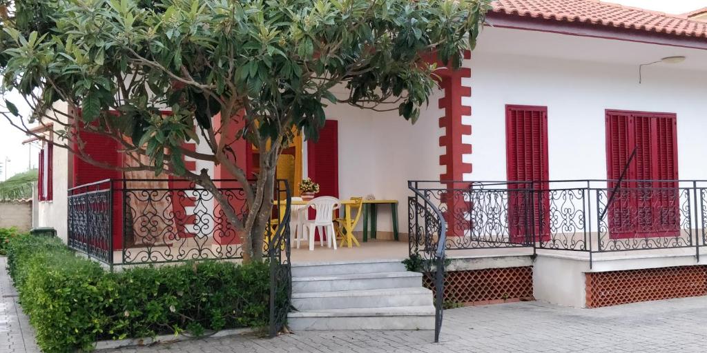 uma casa com portas vermelhas e escadas e uma árvore em Villa Lina em Castel Volturno