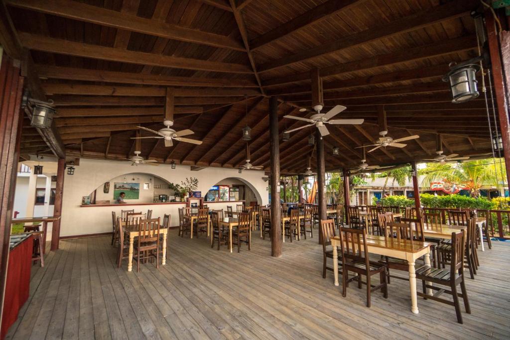 a restaurant with wooden tables and chairs and ceilings at Splash Inn Dive Resort & Villas in West End