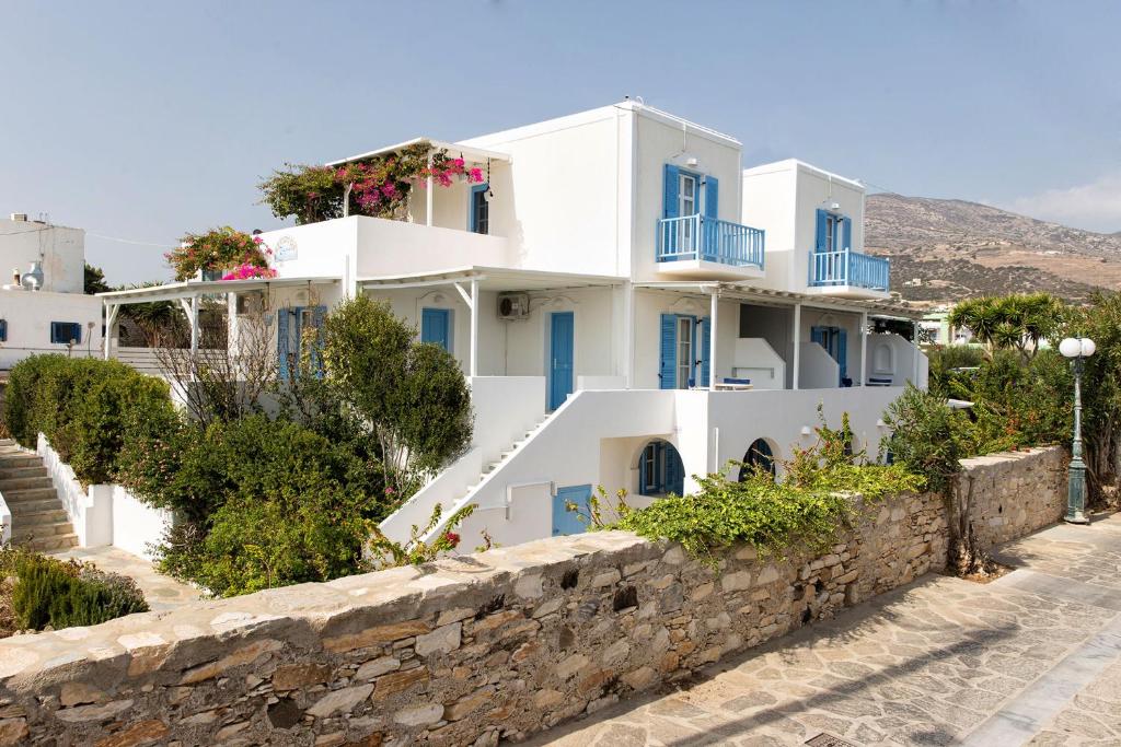 a white house with blue windows and a stone wall at Apartments Tarsa in Drios