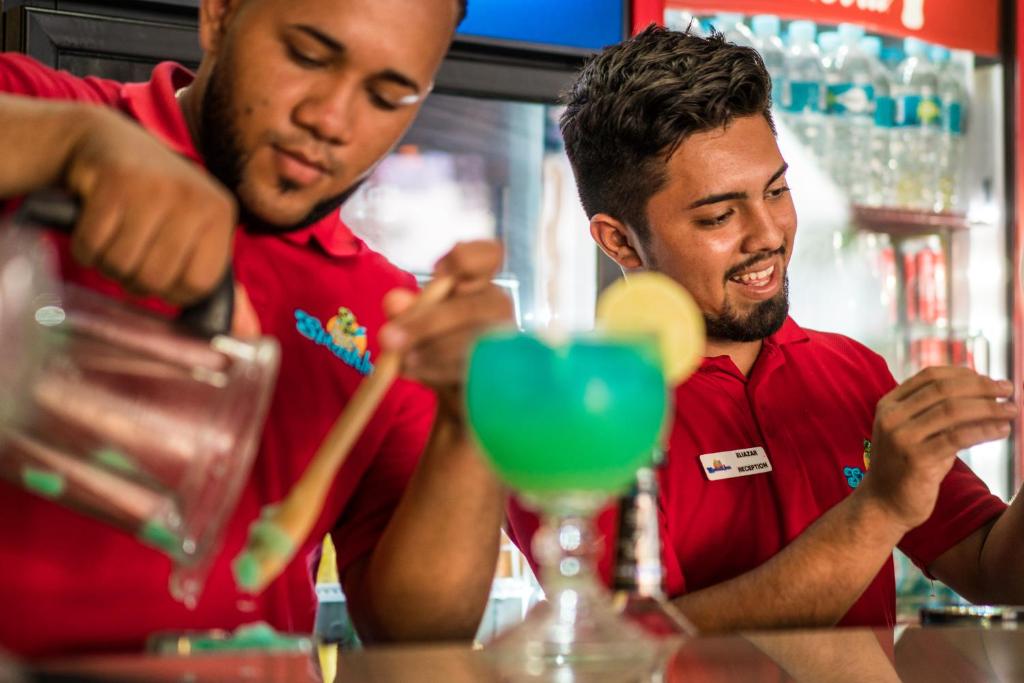 two men standing at a bar preparing drinks at Splash Inn Dive Resort & Villas in West End