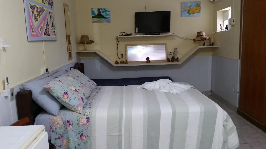 um pequeno quarto com uma cama e uma televisão em Chalé Casa Factur em Fernando de Noronha