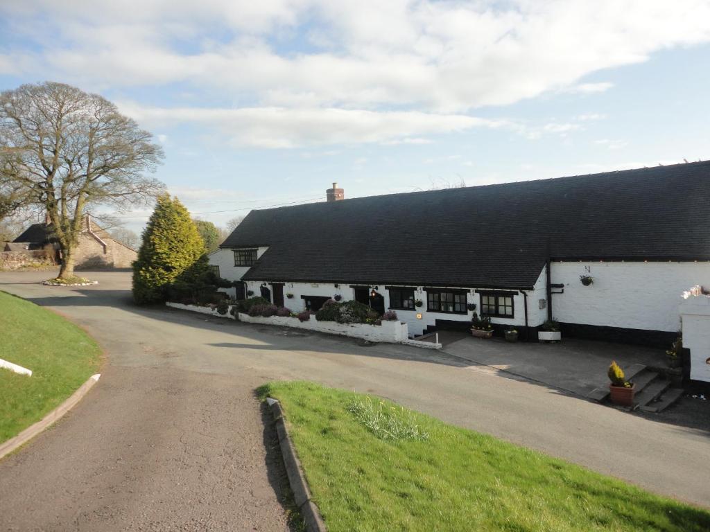 a white house with a black roof and a driveway at The Dog & Partridge Country Inn in Ashbourne