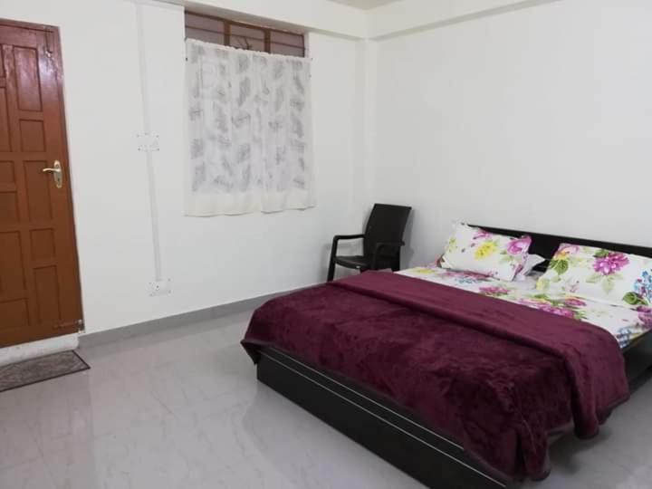 a bedroom with a bed and a chair in it at Delight Homestay in Cherrapunji