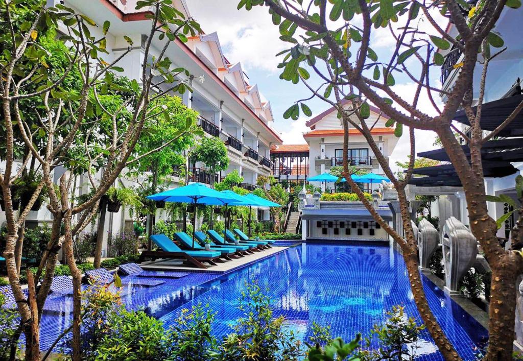 a swimming pool with chairs and umbrellas next to a building at Khmer Mansion Residence in Siem Reap