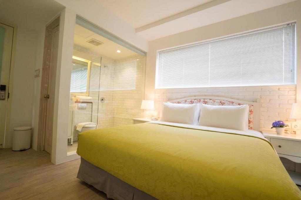 a bedroom with a large yellow bed and a bathroom at Summerbird - Bed and Brasserie in Bandung