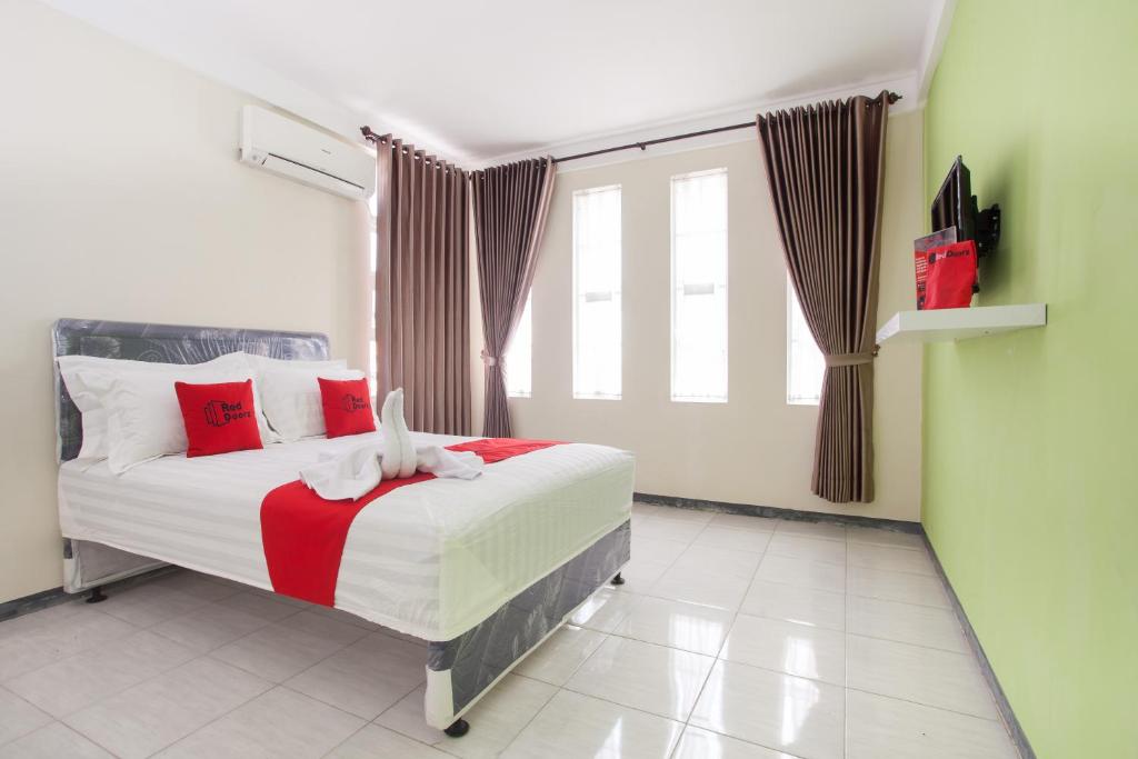 a bedroom with a bed with red pillows and a window at RedDoorz near Museum Angkut Batu 2 in Malang