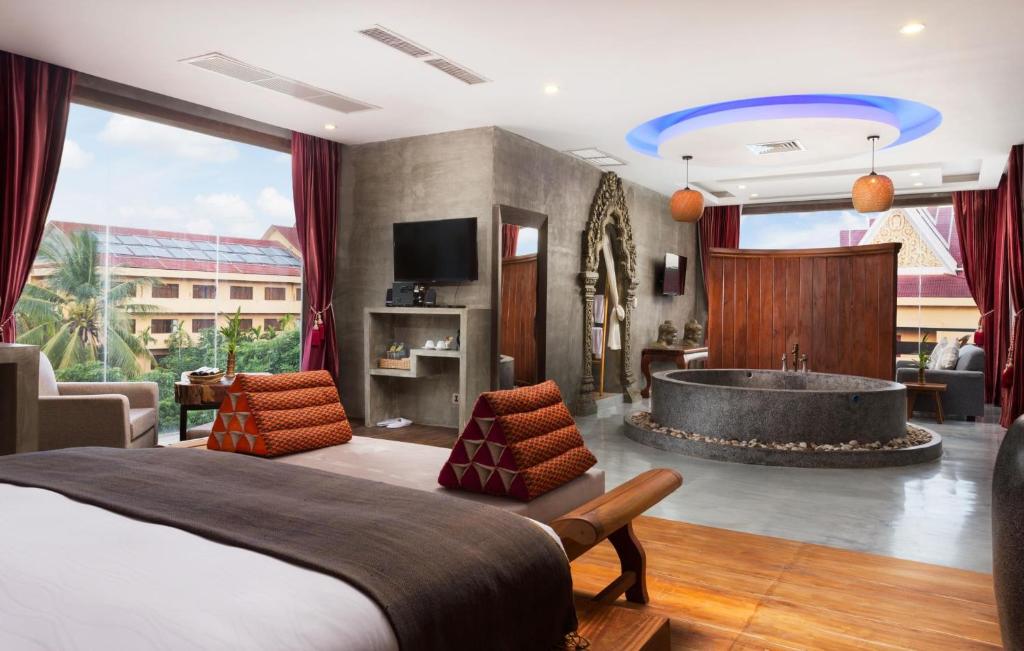 Cambana d'Angkor Suites في سيام ريب: غرفة نوم مع سرير وحوض استحمام في غرفة