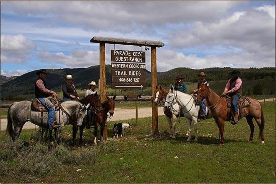 a group of people riding horses next to a sign at Parade Rest Ranch in West Yellowstone
