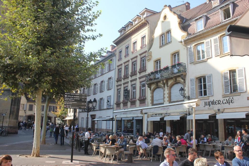 a group of people sitting at tables on a city street at lesboisjolis in Colmar