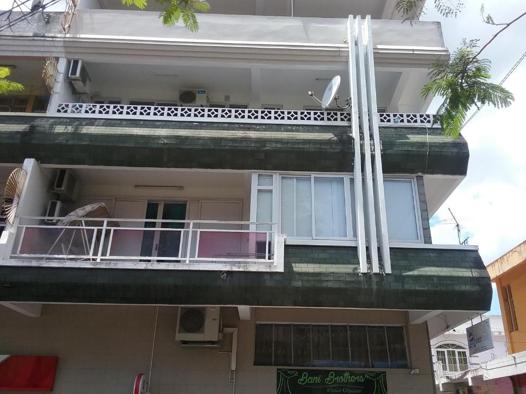 een hoog gebouw met een balkon en een bord erop bij La Plaine Verte Guesthouse in Port Louis