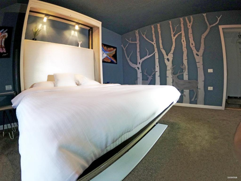 Apulum Gardens في ألبا يوليا: غرفة نوم مع سرير أبيض كبير مع أشجار على الحائط
