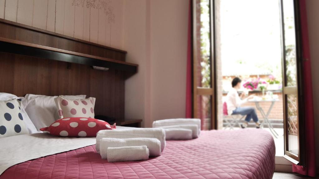 1 dormitorio con cama rosa con almohadas y balcón en Hotel EMI, en Bolonia