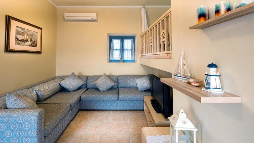 a living room with a blue couch and a television at Amazing House in Halki in Halki
