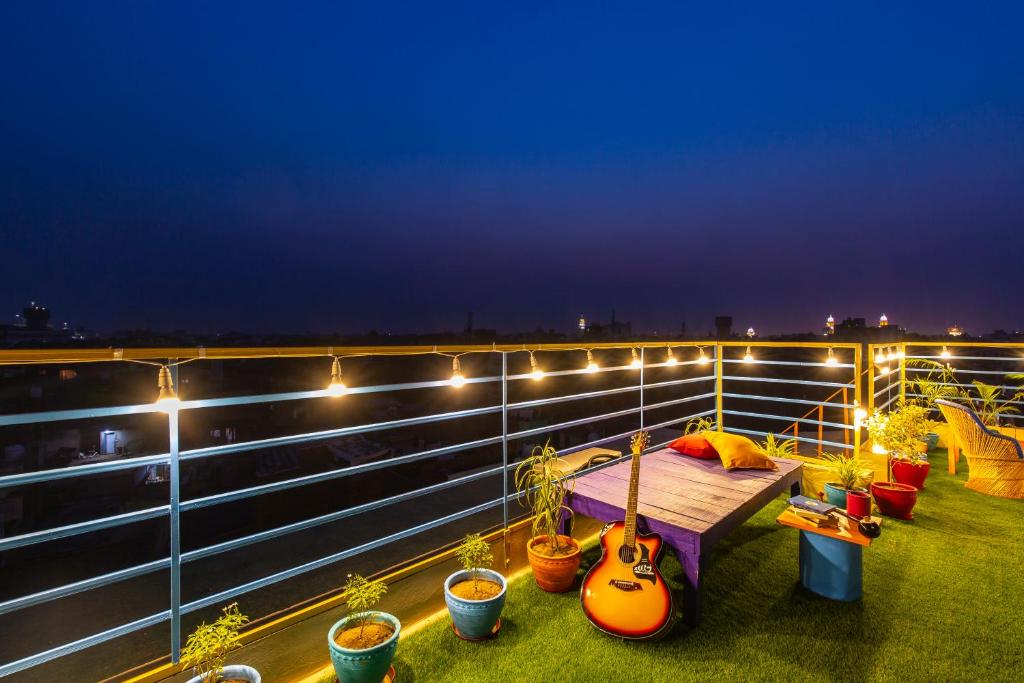 a balcony with a bed with guitars and potted plants at Madpackers Amritsar in Amritsar