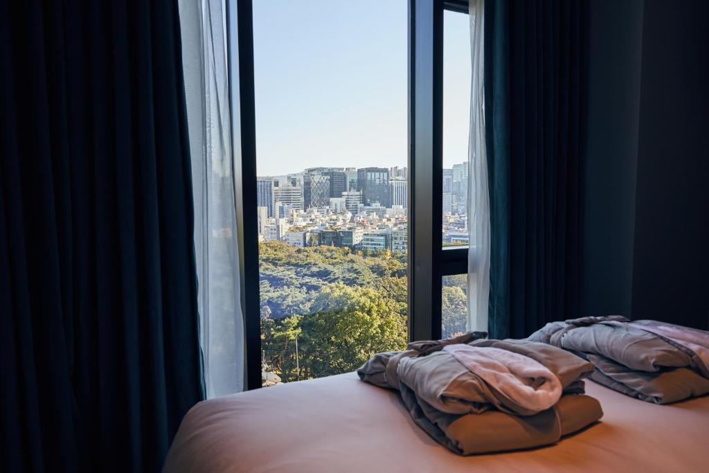 a bed in a room with a large window at Hotel Crescendo Seoul in Seoul
