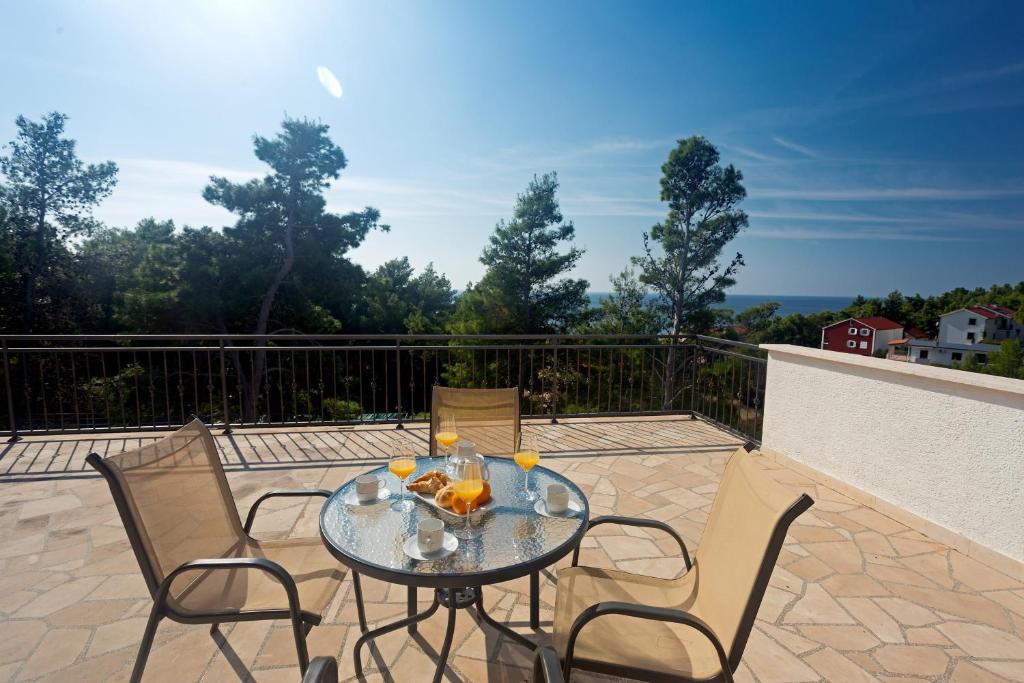 a glass table and chairs on a patio at Lovely apartments Balić in Ivan Dolac