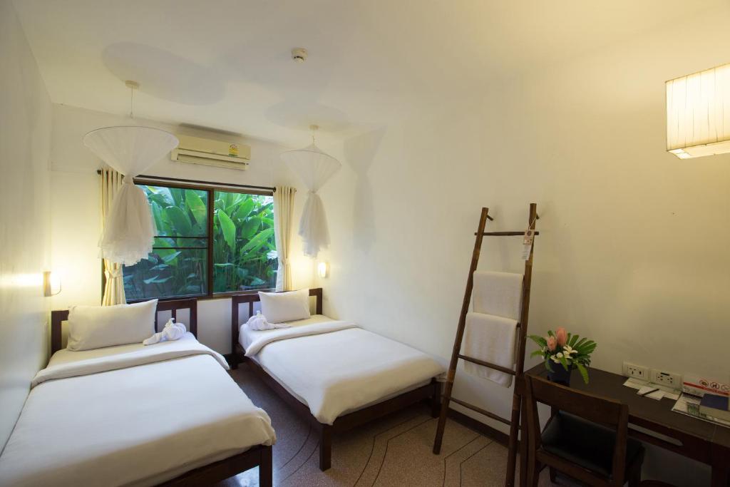 a room with two beds and a desk and a window at Eco Resort Chiang Mai in Chiang Mai