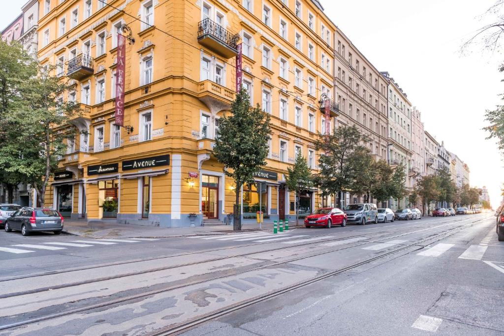un edificio amarillo en una calle de la ciudad con coches aparcados en La Fenice en Praga