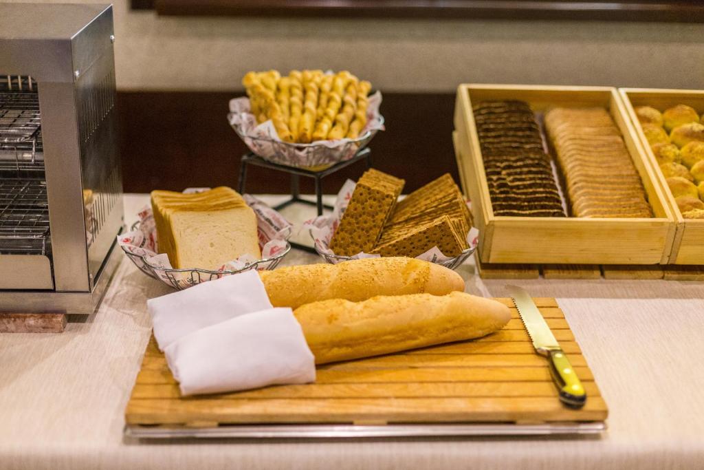 a loaf of bread on a cutting board next to some food at AZIMUT Hotel Siberia in Novosibirsk
