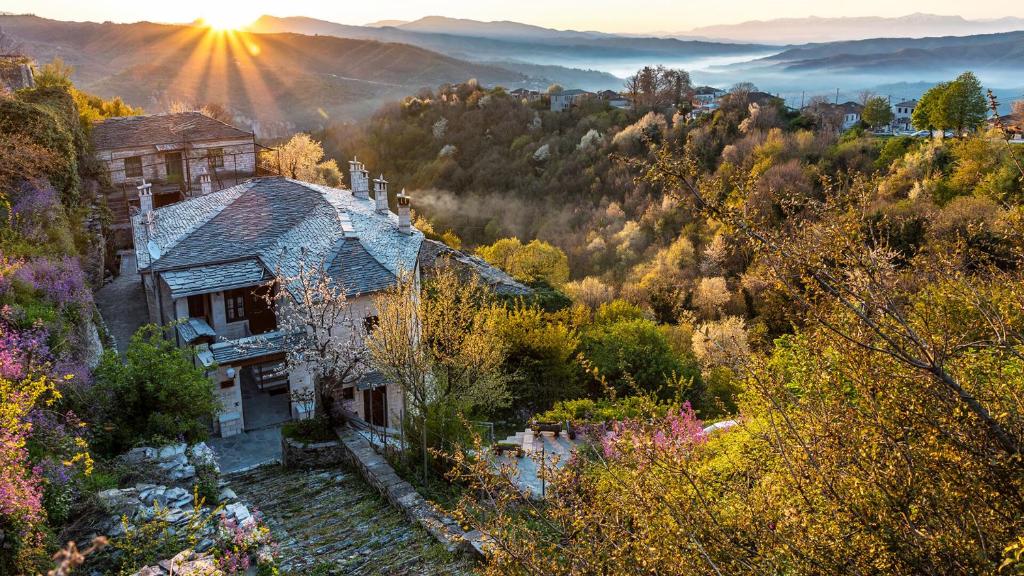 a house sitting on top of a hill with the sun setting at Archontiko Evridikis in Vitsa